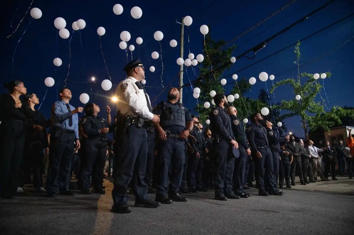 NYPD officers releasing white balloons at night vigil